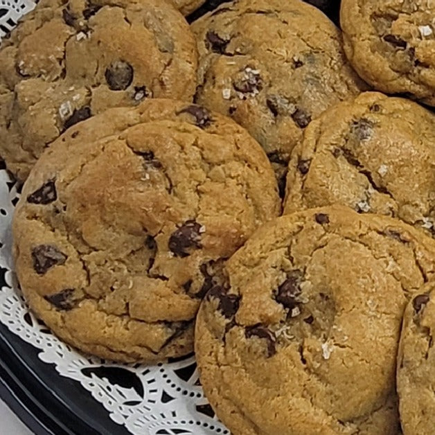 Chocolate chip cookies on a black plate with a white doily